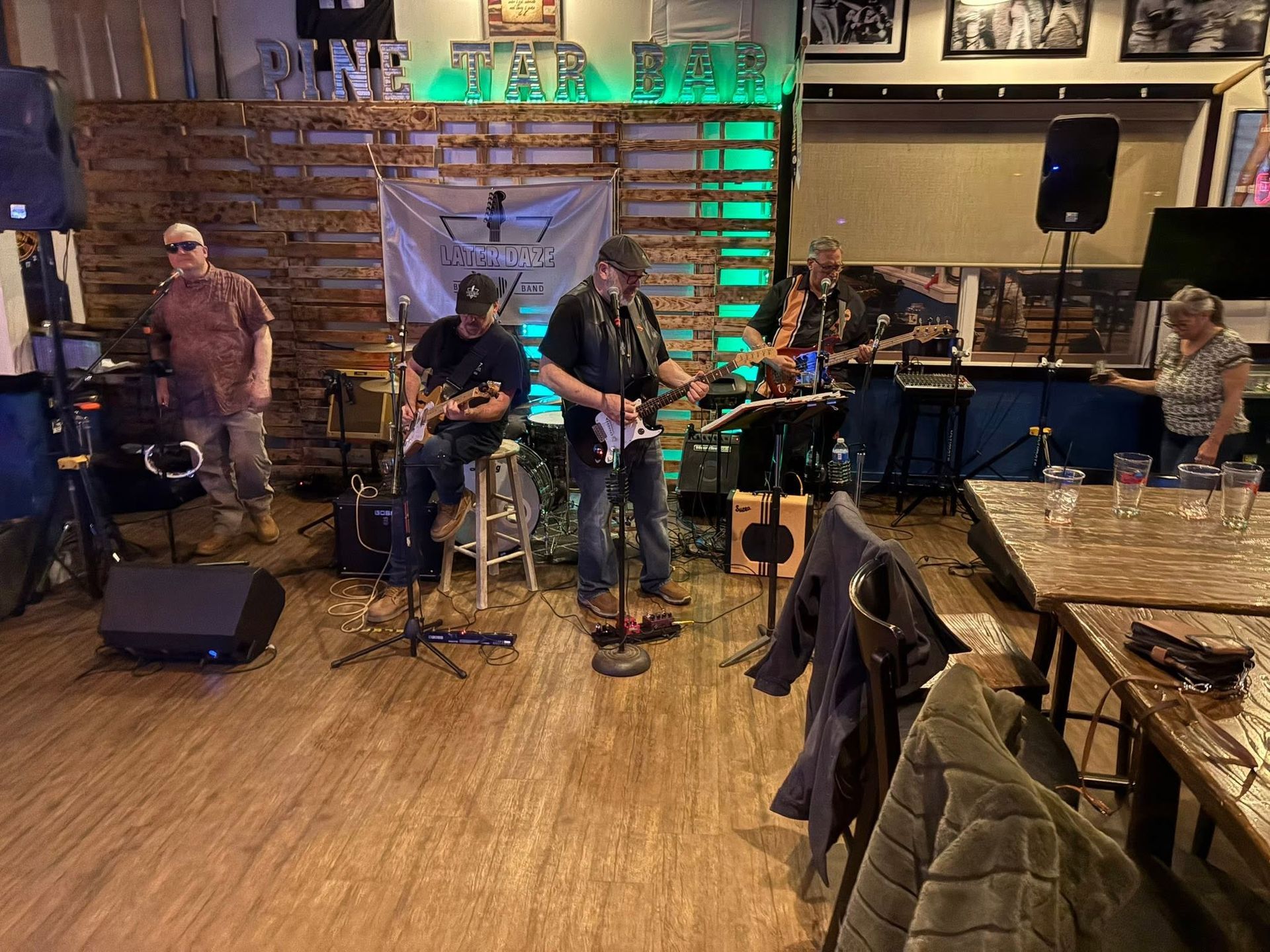 Live band performing on a wooden stage in a restaurant with brick walls and green lighting