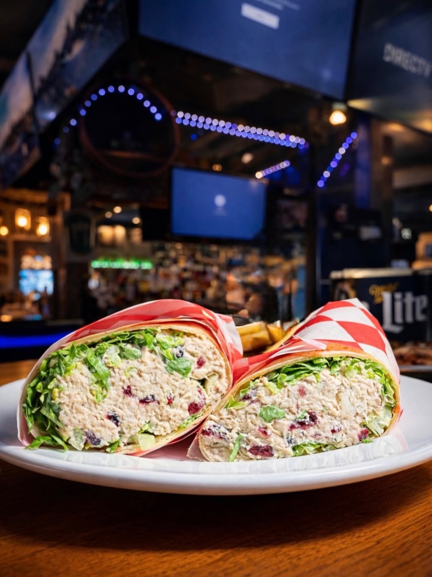 Cut burrito on a plate in a dimly lit restaurant, with colorful fillings visible.