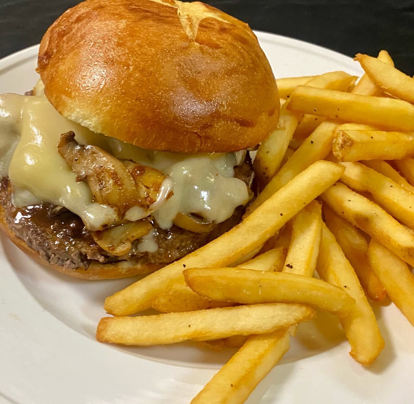 Cheeseburger with melted cheese and fries on a white plate