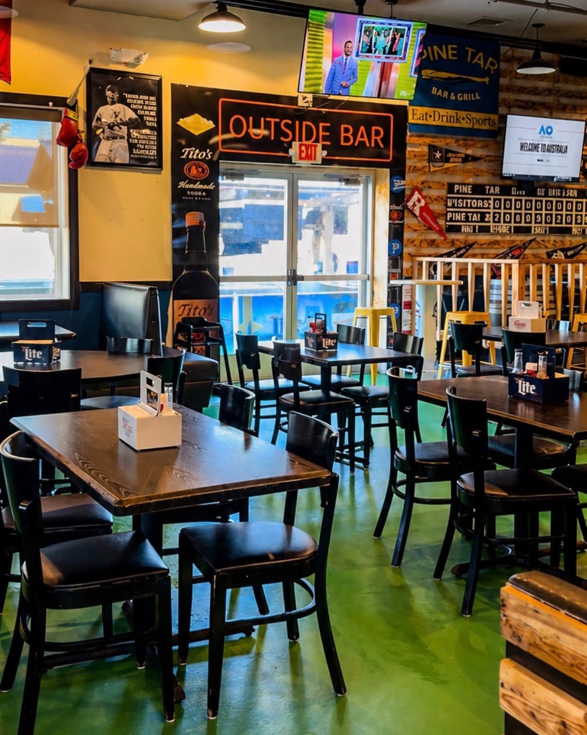 Empty cozy bar with tables, stools, and neon signs, including an “Outside Bar” sign above the back area.