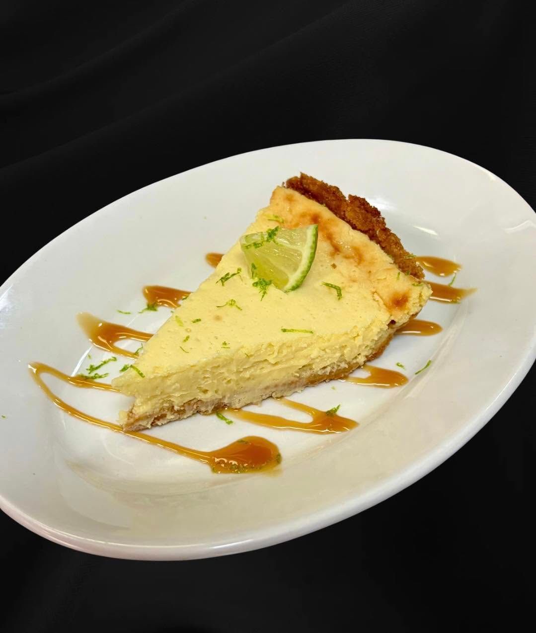 Slice of lime cheesecake on a white plate, drizzled with caramel sauce