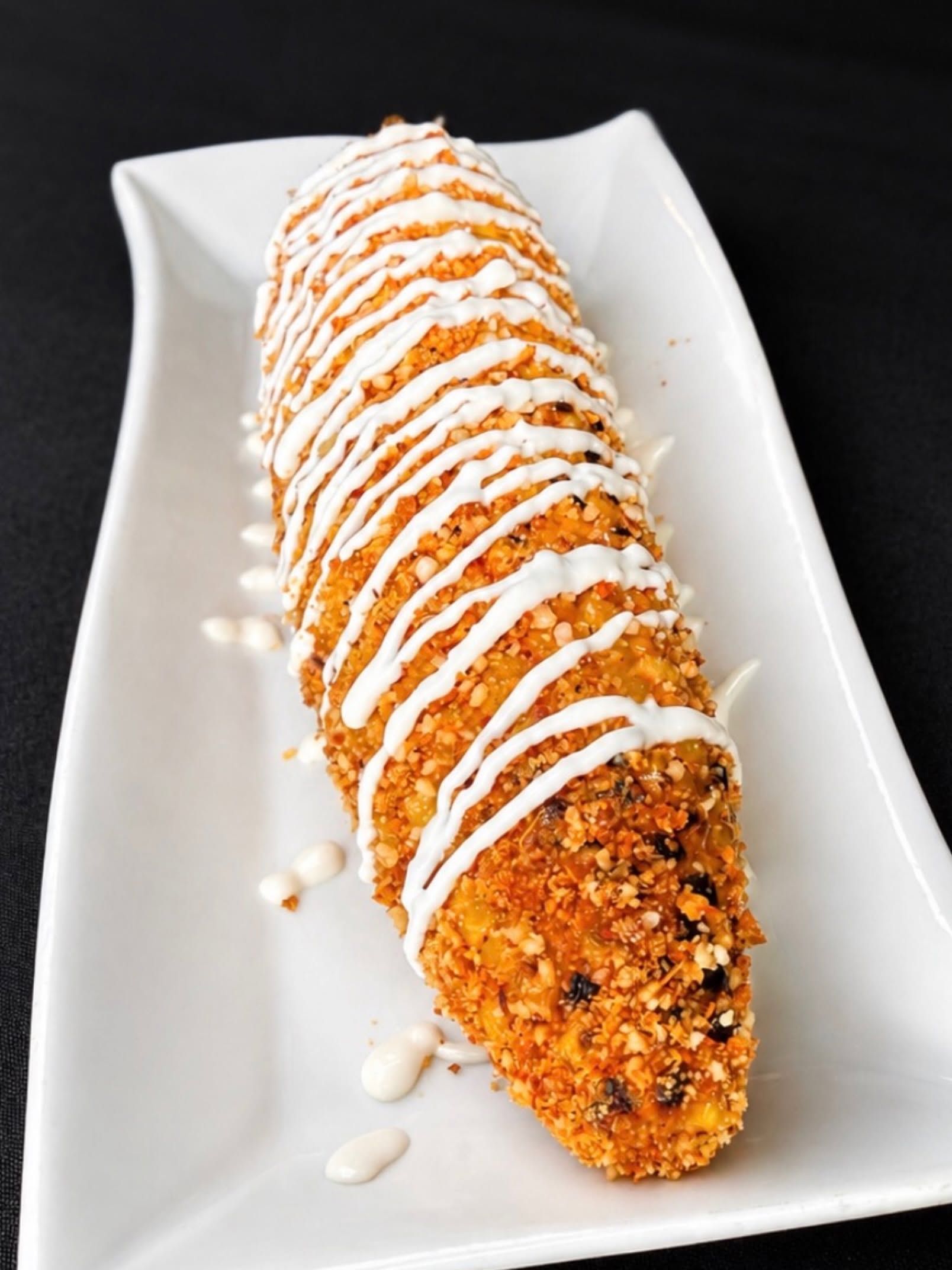 Drizzled churro on a white rectangular plate with icing drizzle