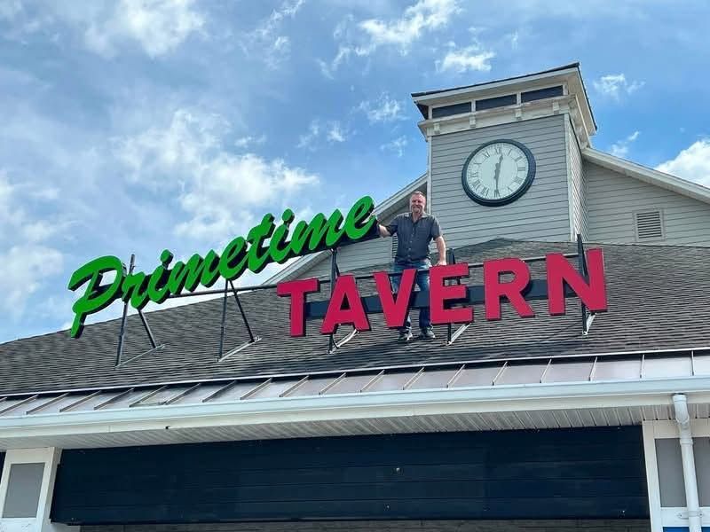 Prime Time Tavern sign on a building with a clock tower under a blue sky