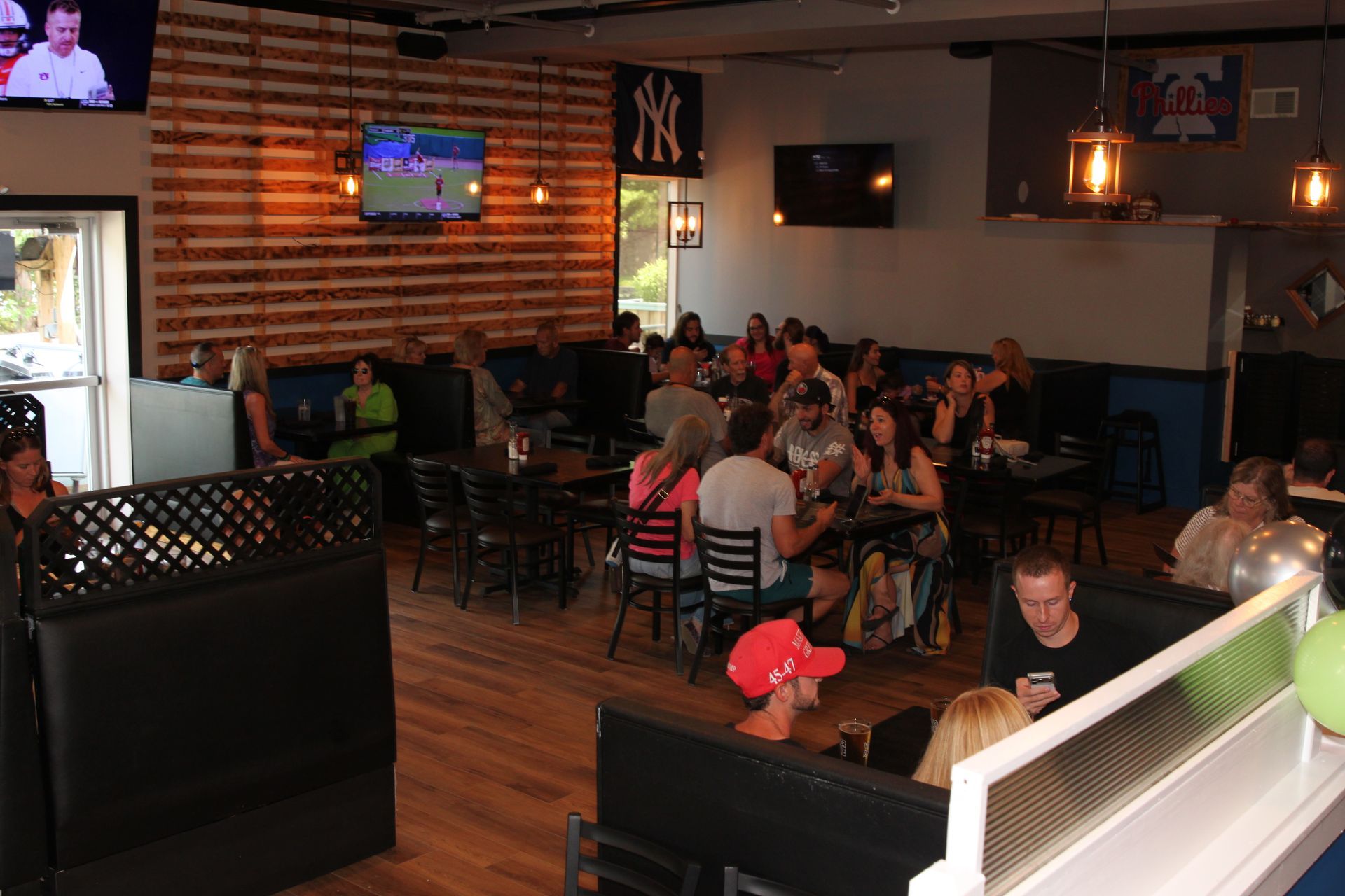 Crowded sports bar with patrons seated at tables and TVs mounted on brick walls