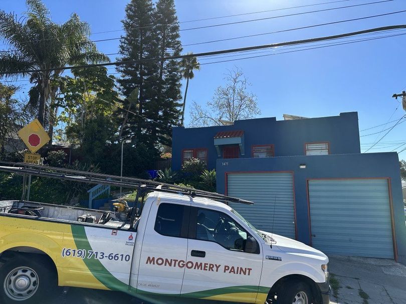 A montgomery paint truck is parked in front of a blue building.