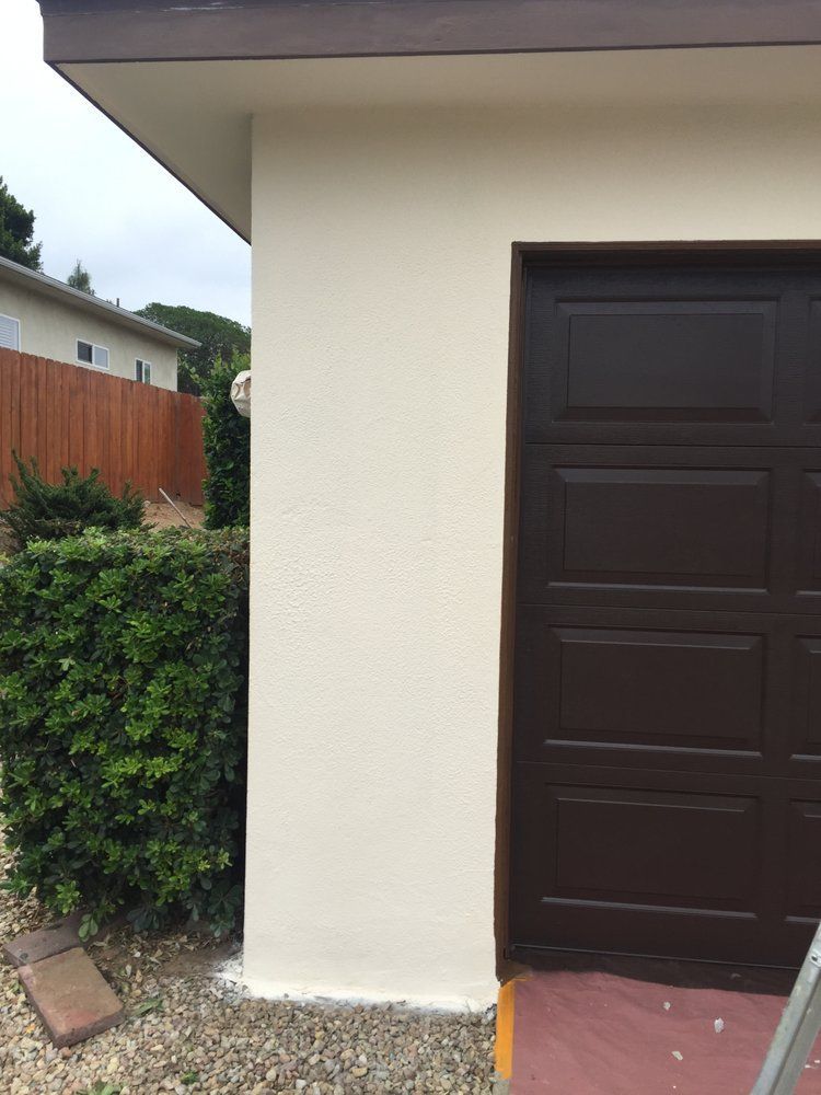 A garage door is being painted on the side of a house.
