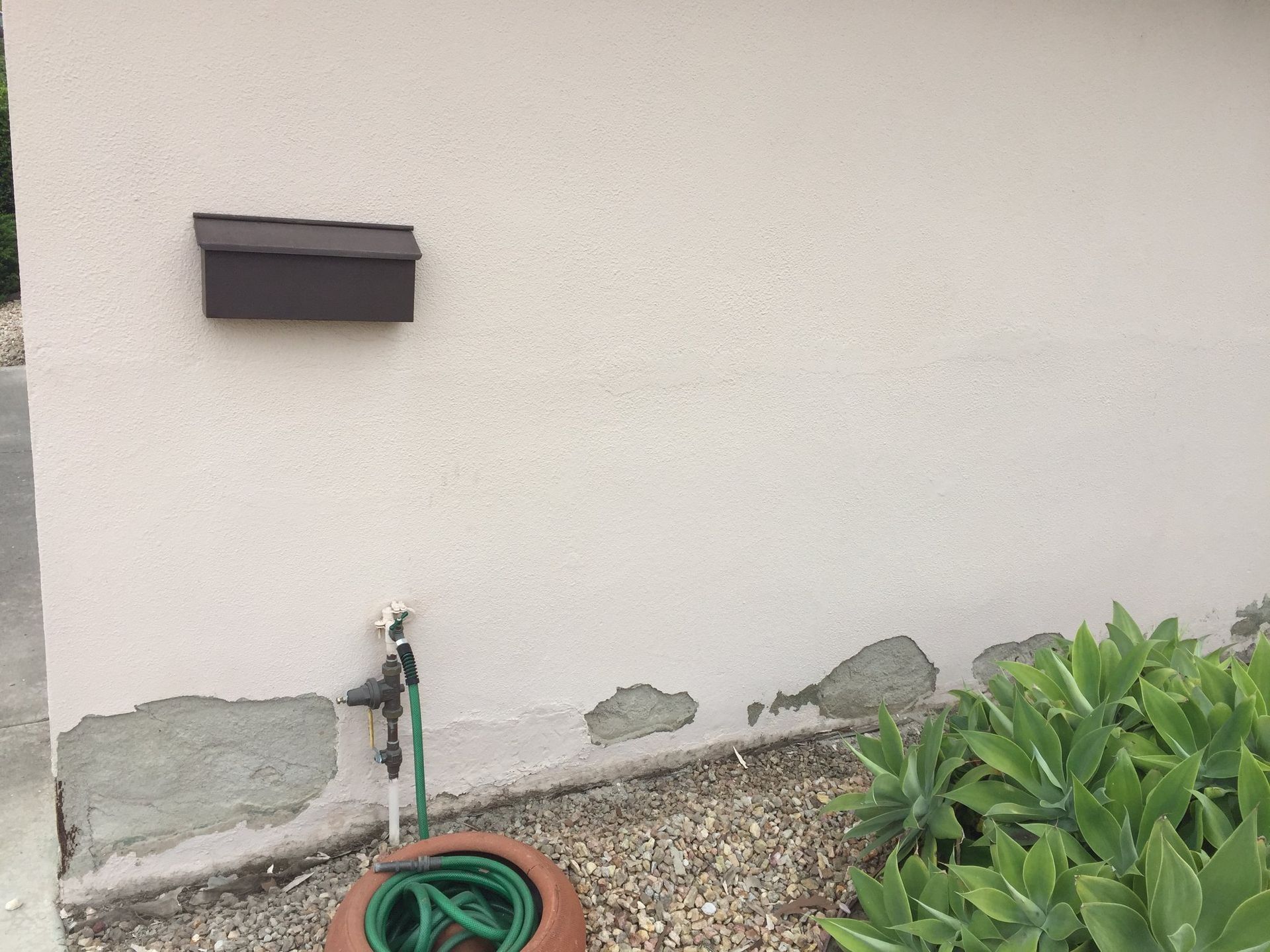 A hose is attached to the side of a building next to a mailbox.