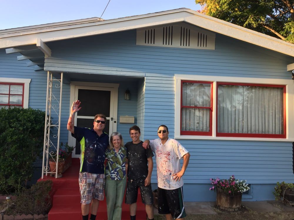 A group of people standing in front of a blue house