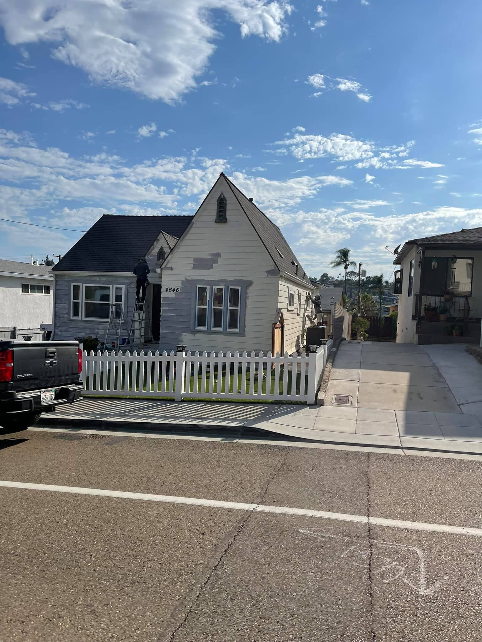 A truck is parked in front of a house with a white picket fence.