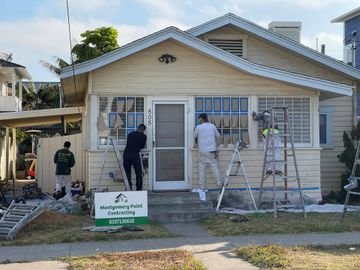 A group of men are painting the side of a house.
