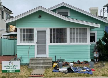A small green house with a sign in front of it.