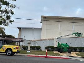 A yellow truck is parked in front of a large building