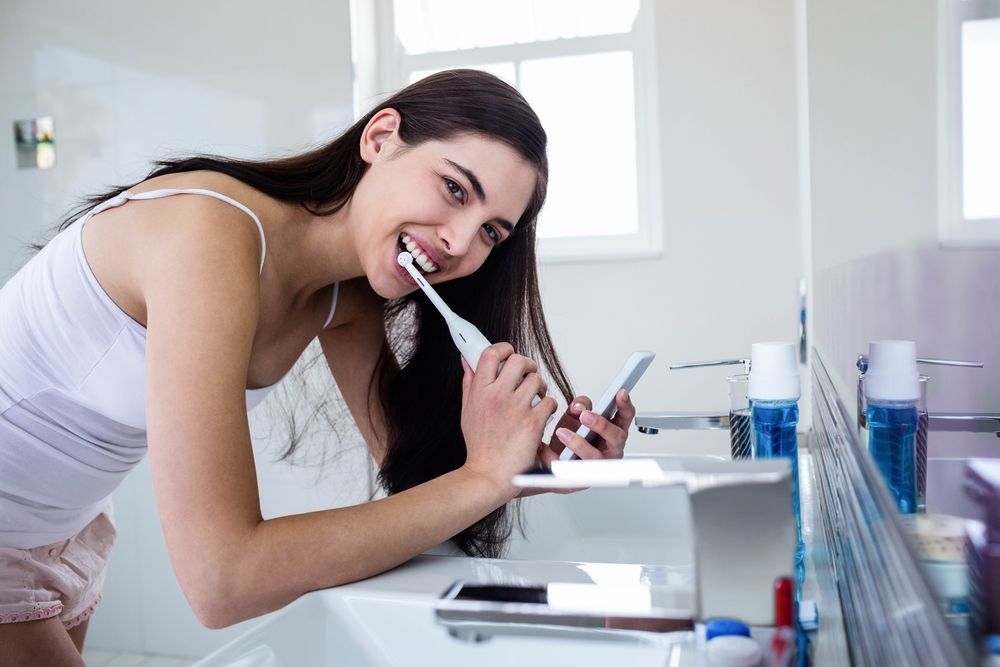 Woman brushing her teeth with an electric toothbrush