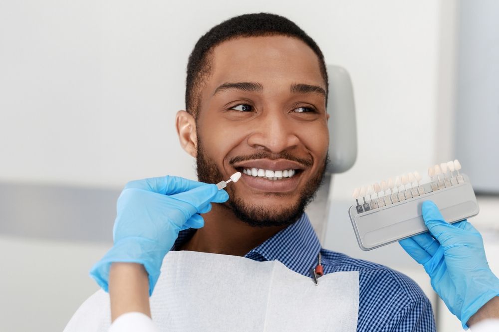 Dentist comparing a patient's tooth shade during cosmetic dental care