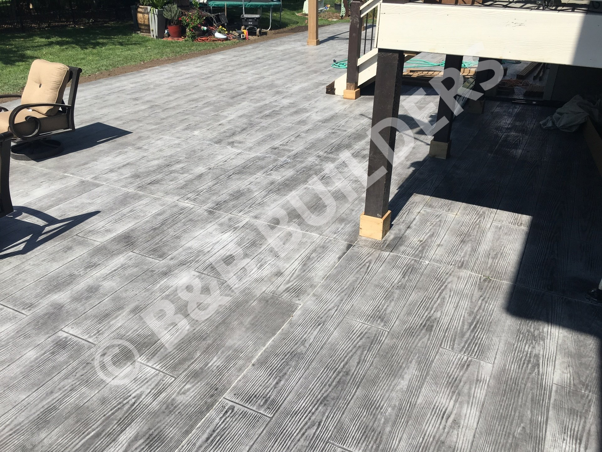 A concrete patio stamped and colored to look like grey wood planks