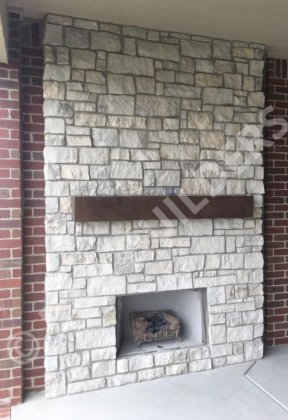Masonry fireplace with inset timber mantel, set into a brick wall