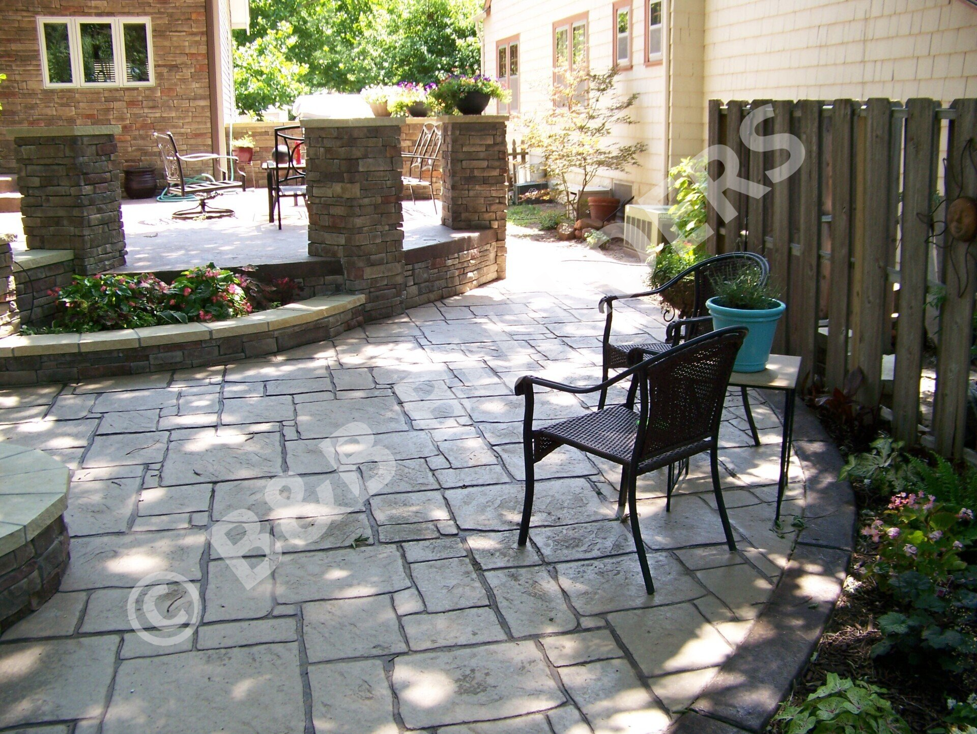 A  stamped concrete faux flagstone patio with chairs and raised area