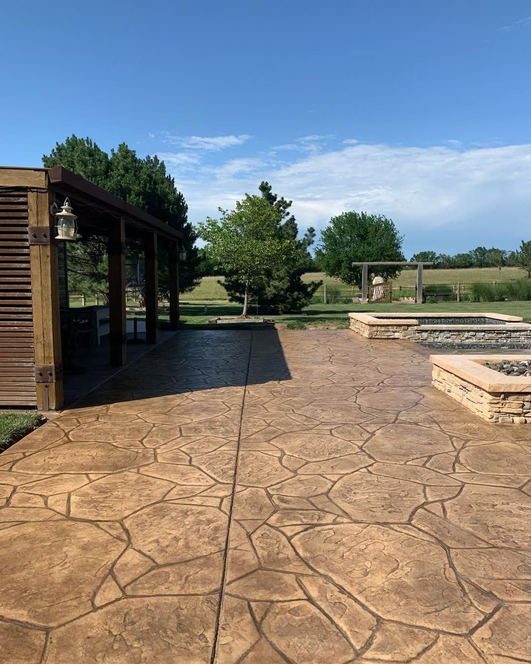 Open-air covered patio structure with post lighting overlooking a Kansas yard