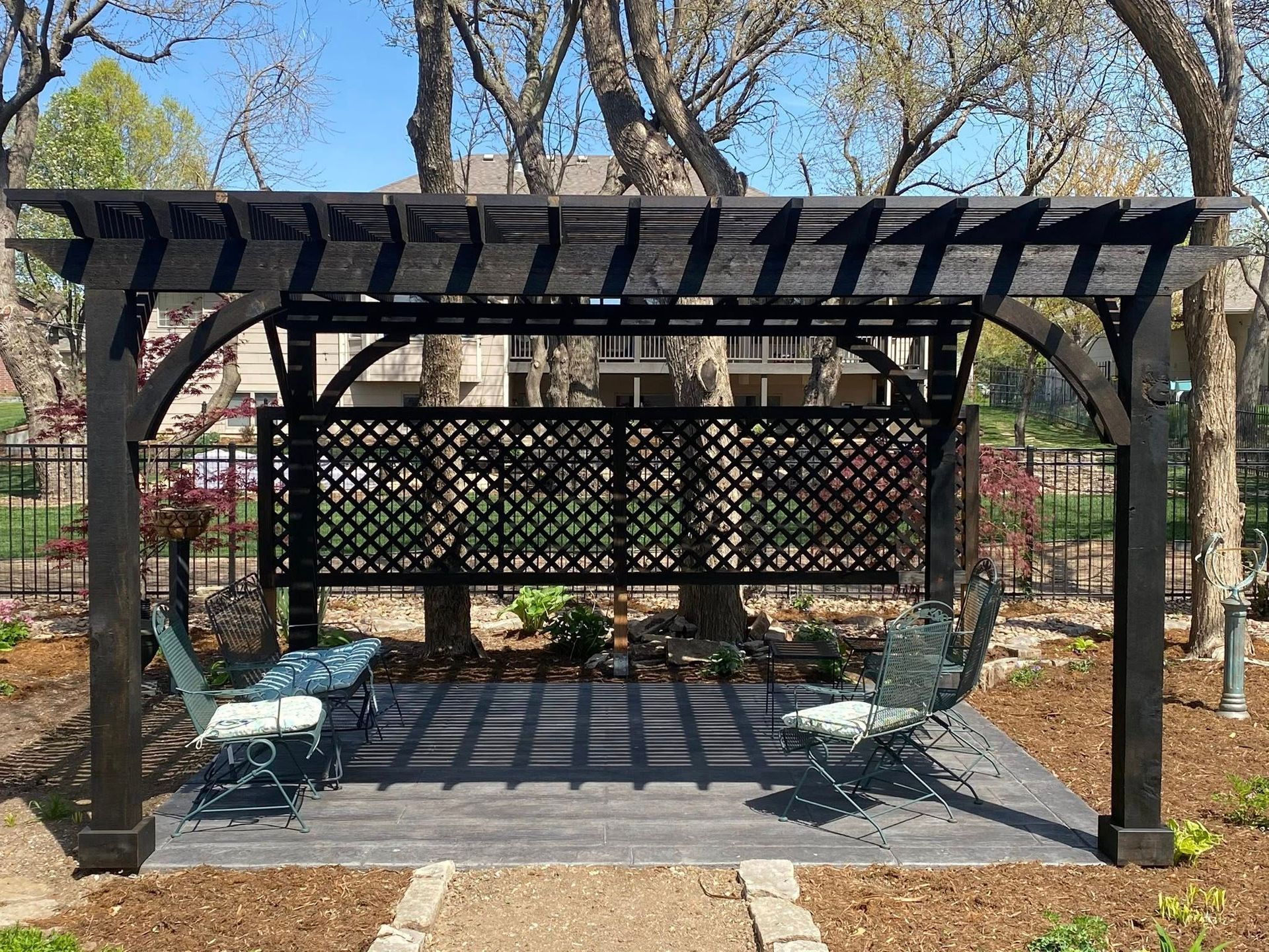 A pergola overlooking a lake with a fire pit in the middle