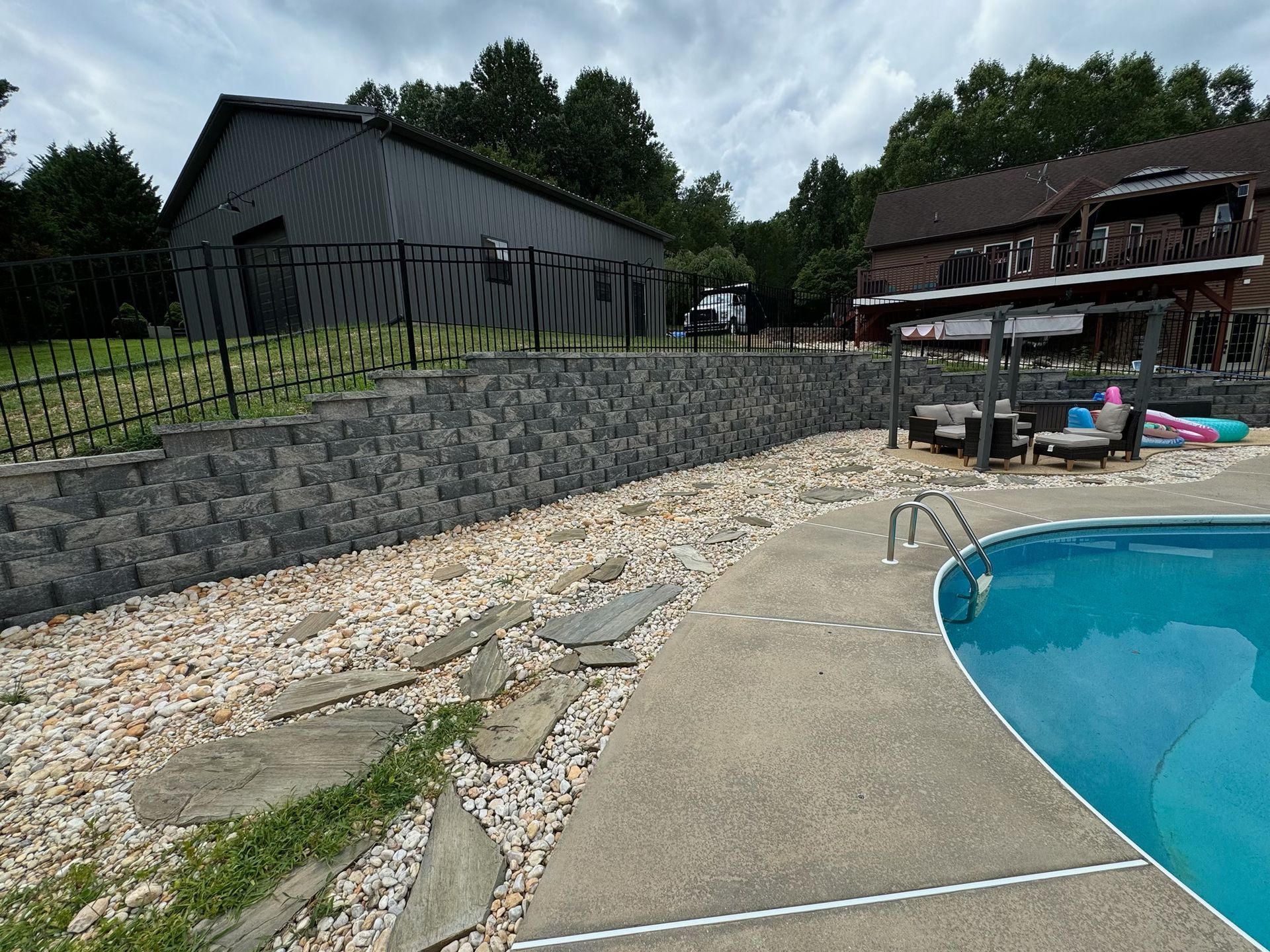A large swimming pool is in the backyard of a house.