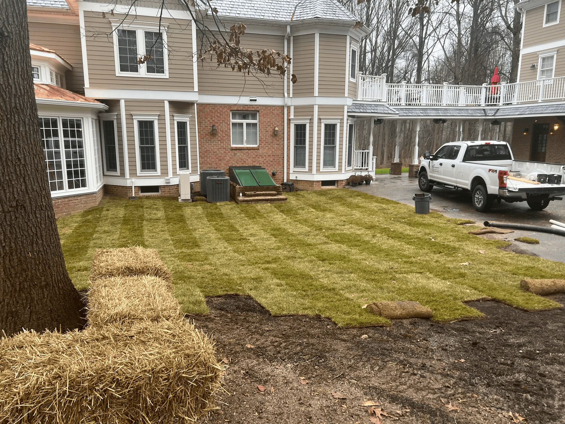 A white truck is parked in front of a house with a lush green lawn.