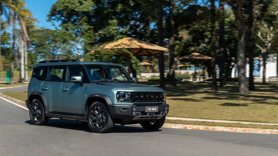 Dark green SUV driving on a tree-lined road on a sunny day