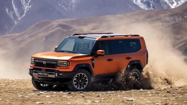 Orange off-road SUV driving through dust in a rocky desert landscape with mountains in the background