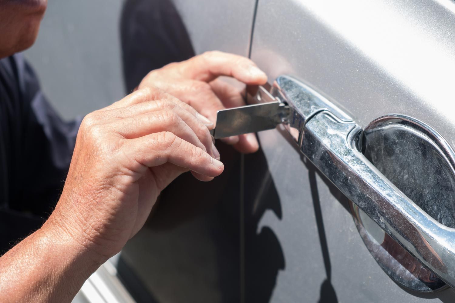 Hands unlocking a silver car door with a key