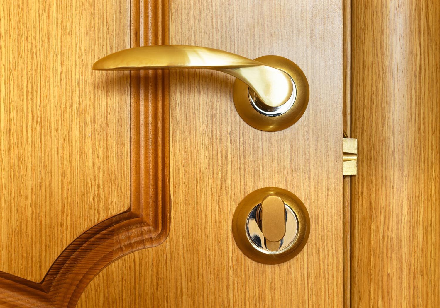 Gold door handle and lock on a wooden door panel
