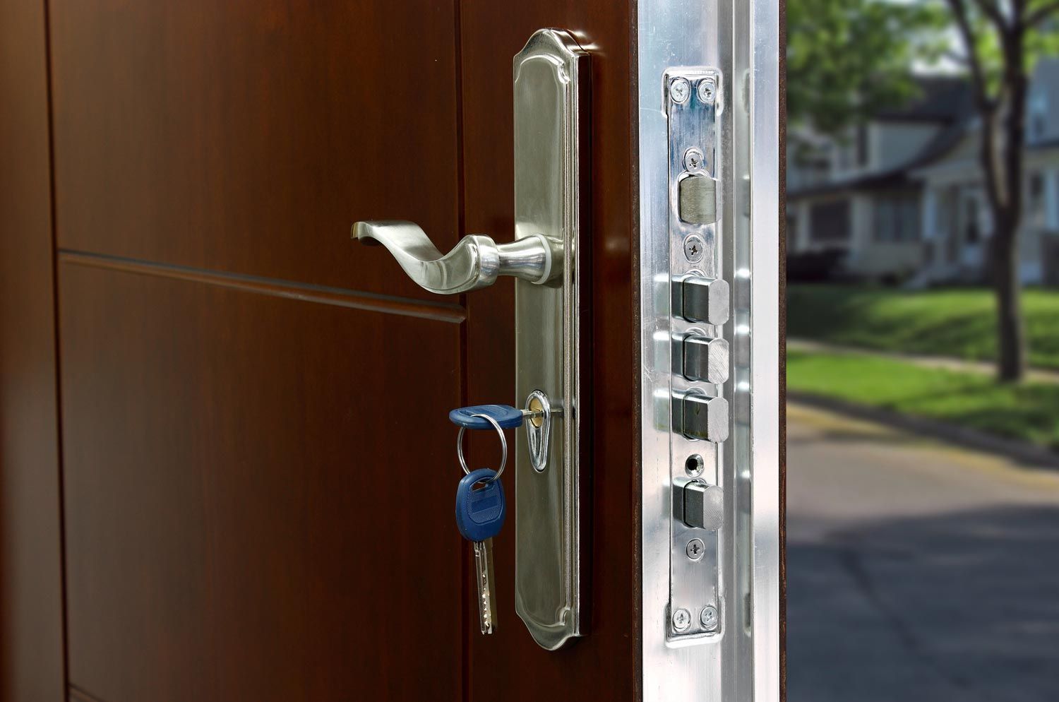 Front door with silver handle and key lock, keys hanging in the lock, doorway open to outside