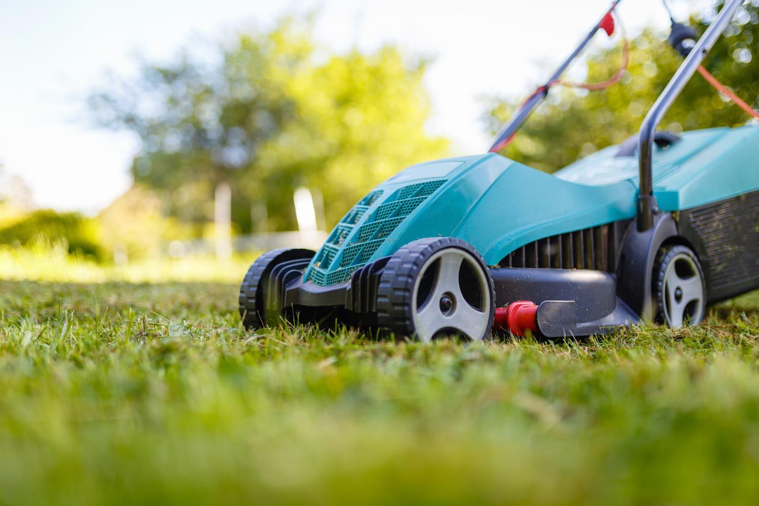 Blue lawn mower on grass in a sunny yard