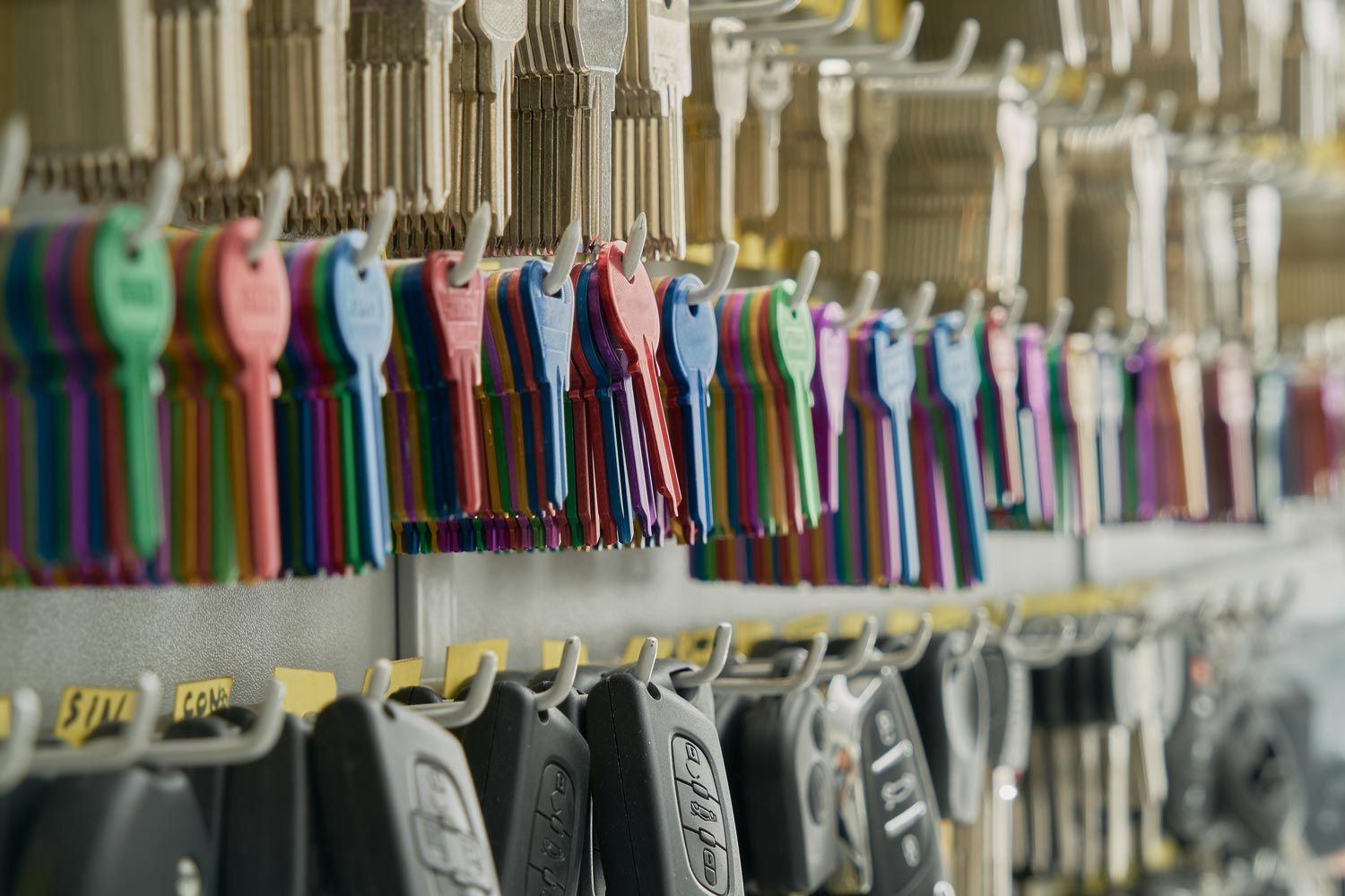 Row of colorful hanging key tags in a hardware store, with gray keys below