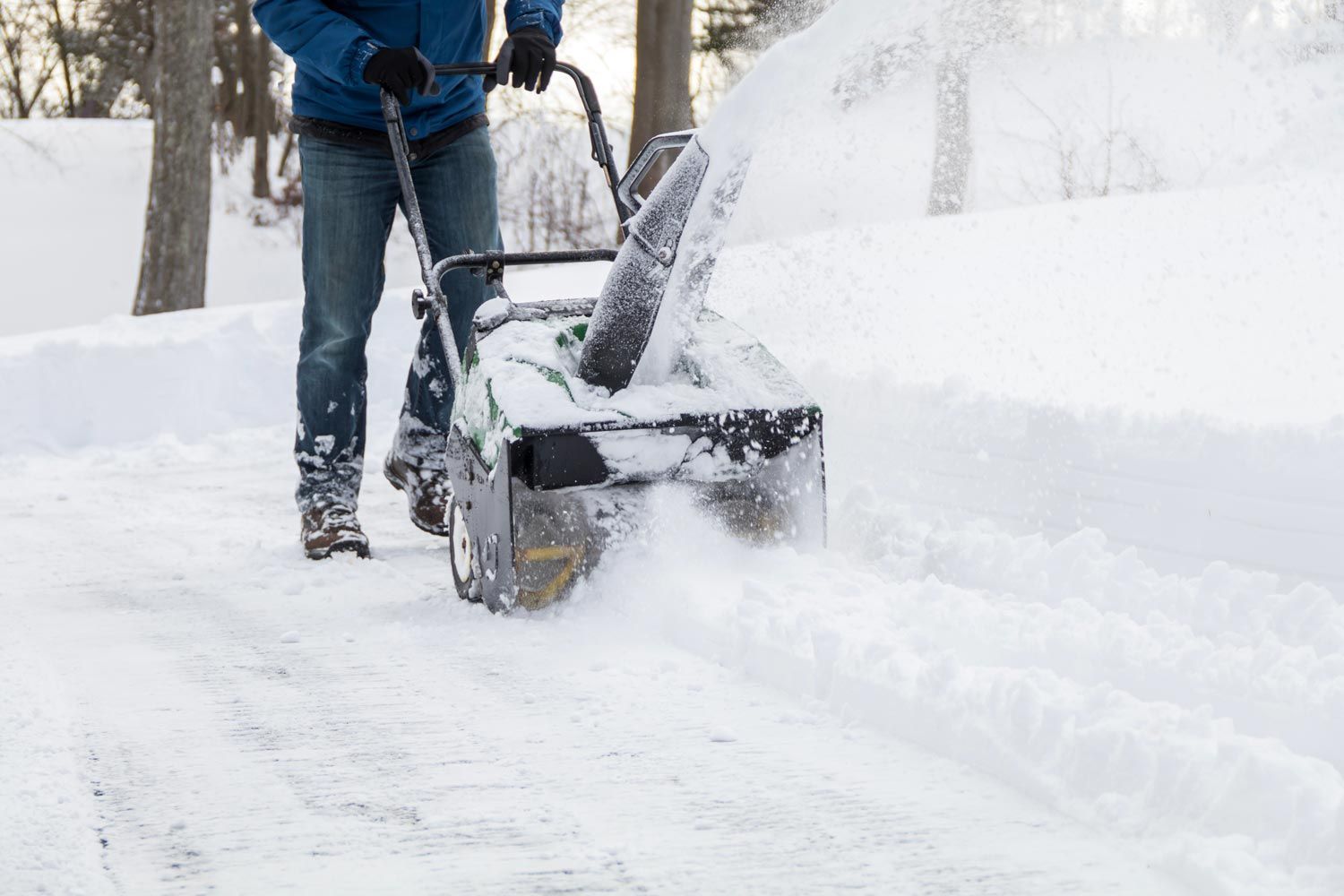 Person clearing snow with a snowblower on a snow-covered walkway
