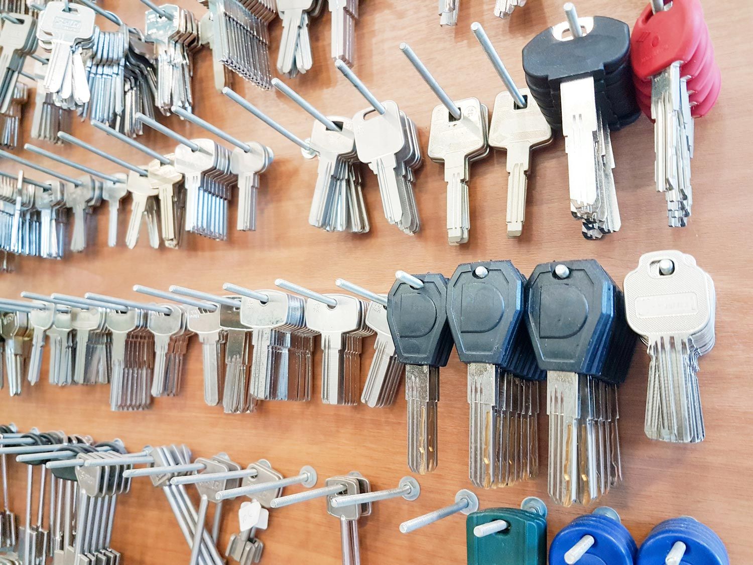 Rows of assorted keys on hooks, with silver, beige, and black key heads against a wall display.