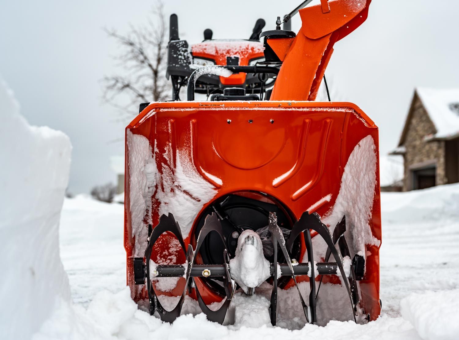 Orange snowblower buried in snow on a snowy residential street