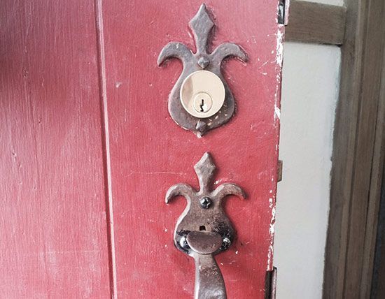 Close-up of a red door with an ornate metal lock plate and keyhole