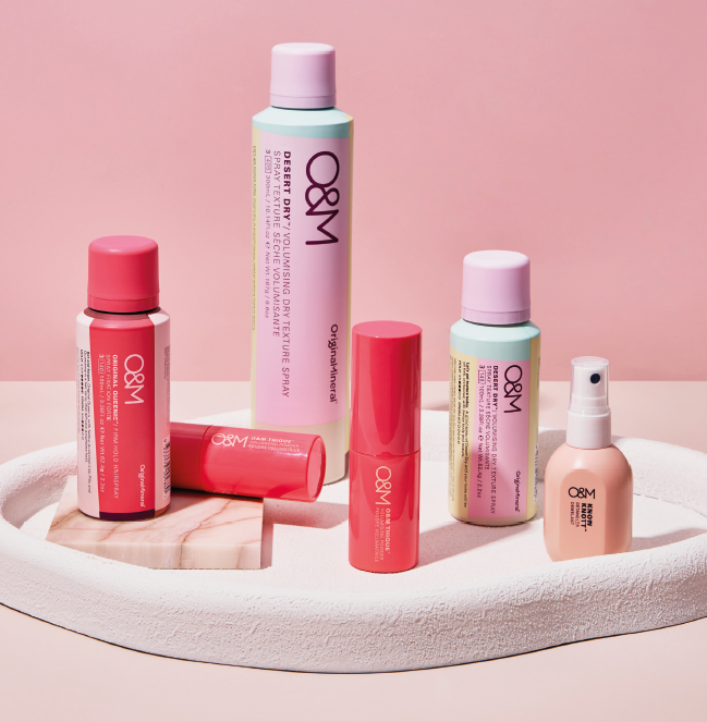 Flaconi e tubetti cosmetici rosa e bianchi su uno sfondo rosa pastello.