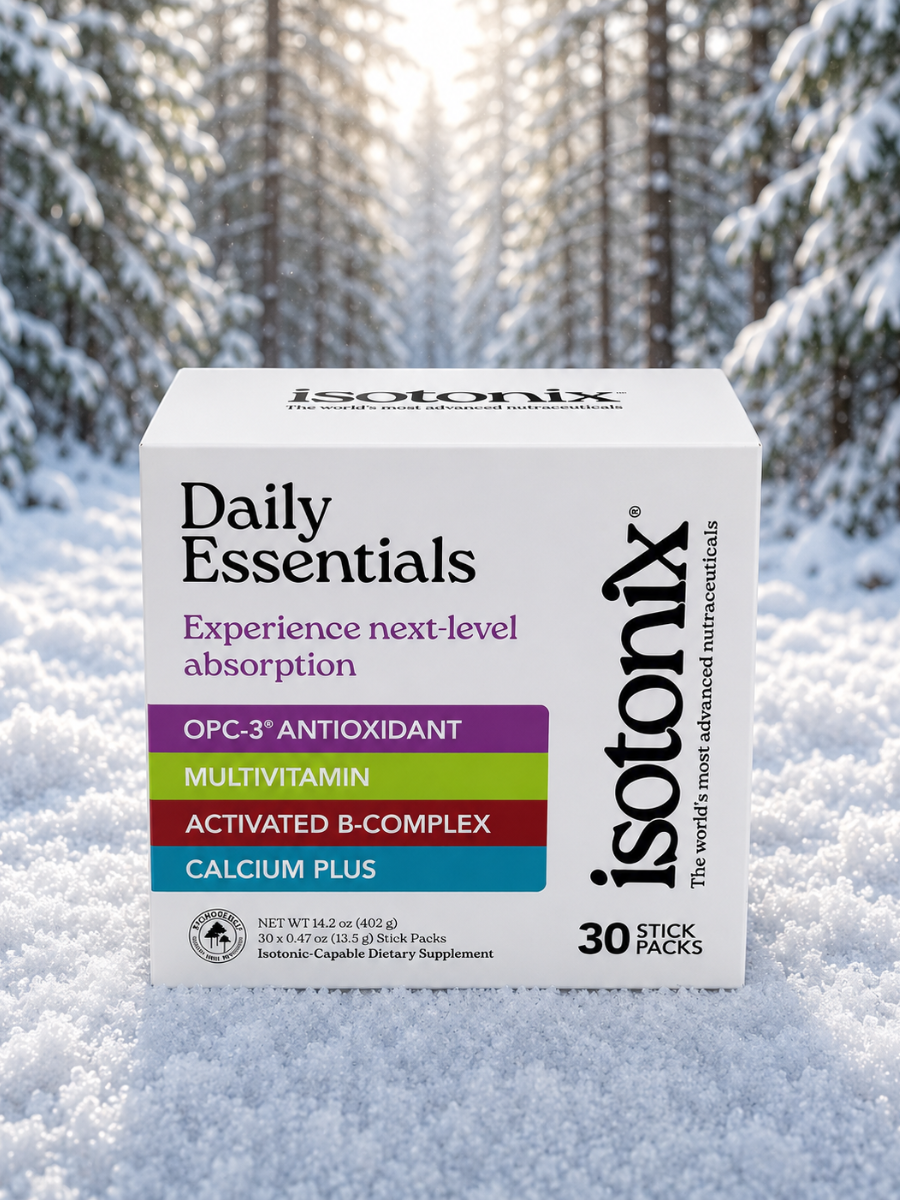 Isotonix Daily Essentials supplement box in white with colorful labels against a snowy forest backdrop