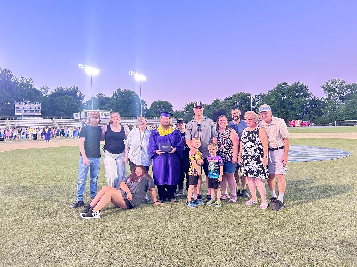Group posing on a sports field at dusk, with stadium lights and trees in the background.