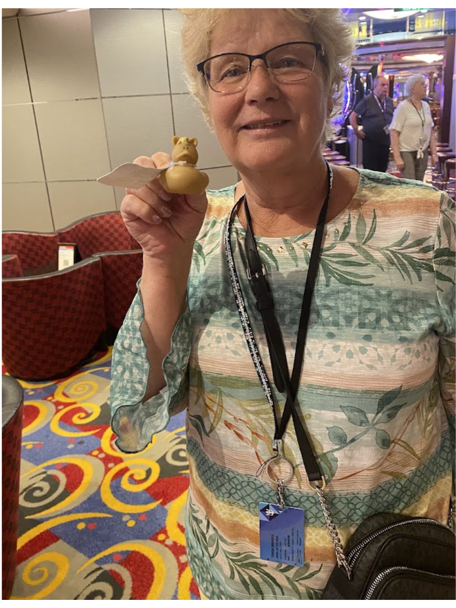 Woman holding a small dessert in a colorful casino lounge, smiling at the camera.