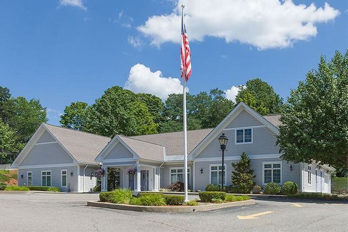 Gray building with American flag flying, trees, and blue sky.