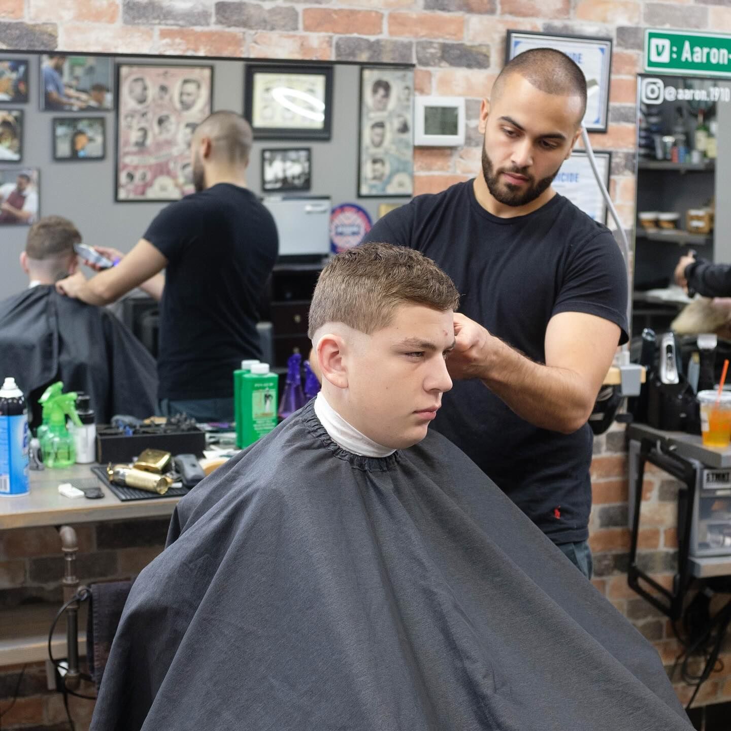 Barber trimming a client's hair in a barbershop with mirrors and grooming tools visible.