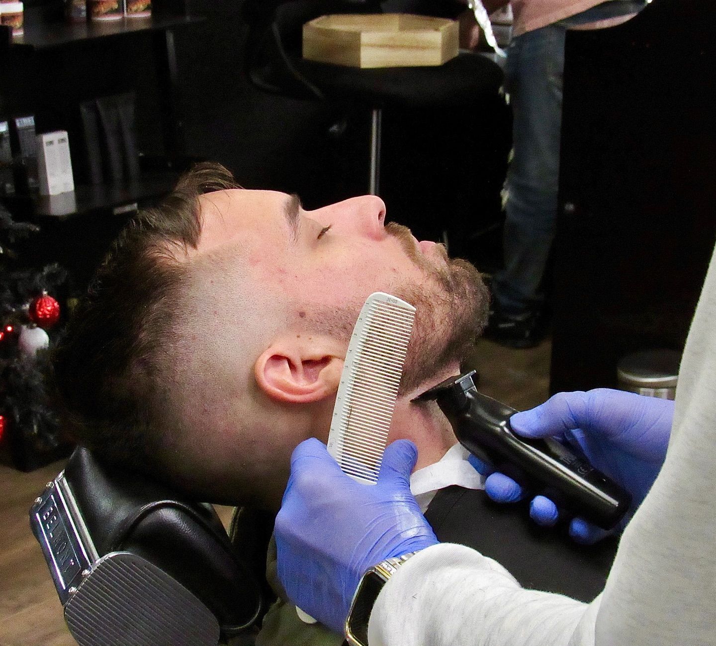 Barber shaving a seated customer’s neck with a straight razor in a barbershop.
