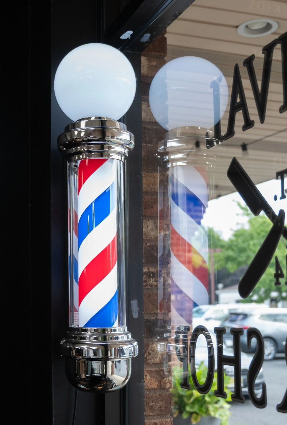 Barber pole with red, white, and blue stripes hanging in a shop window