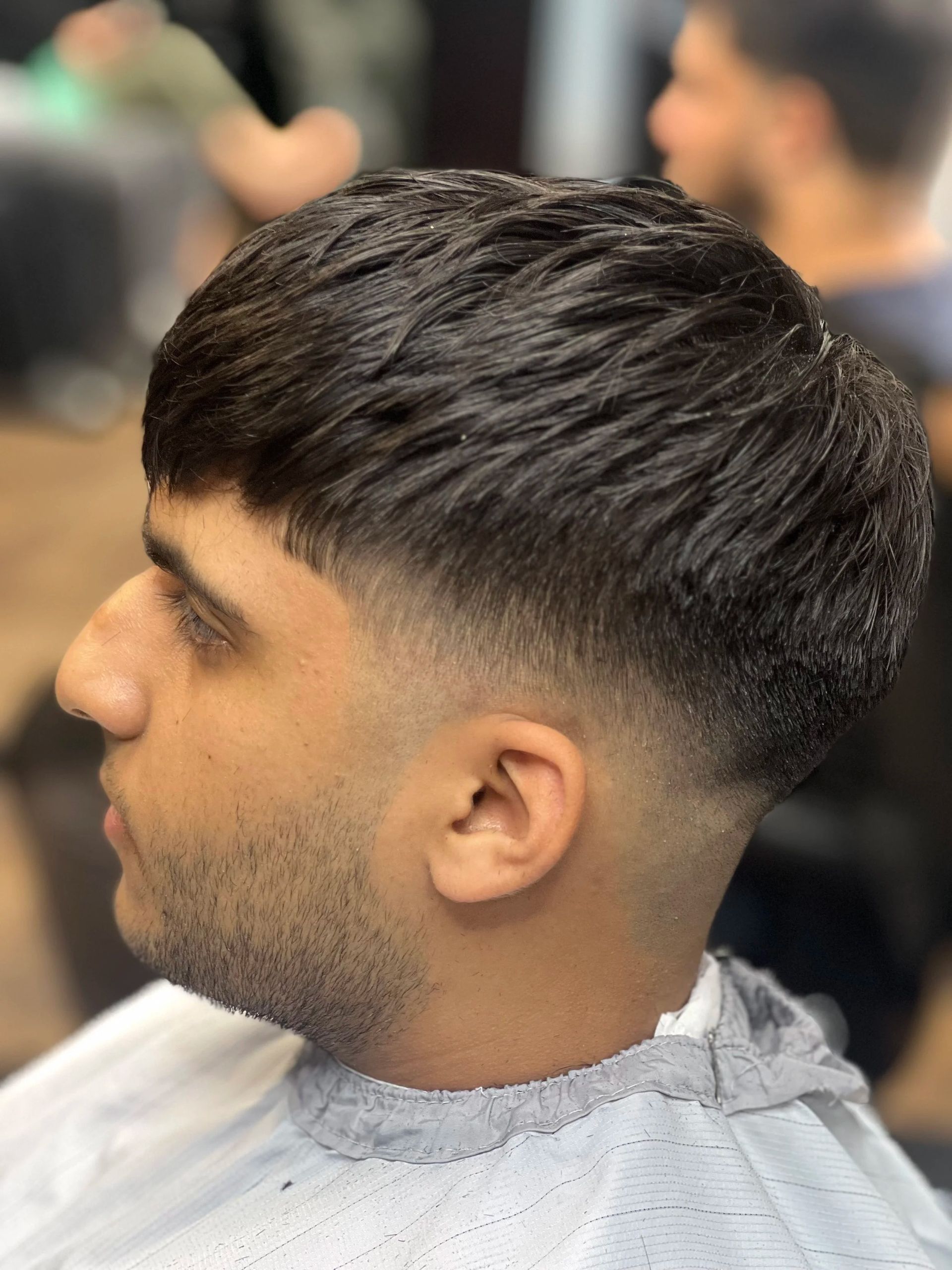 Side profile of a short textured fade haircut on a man in a barber chair