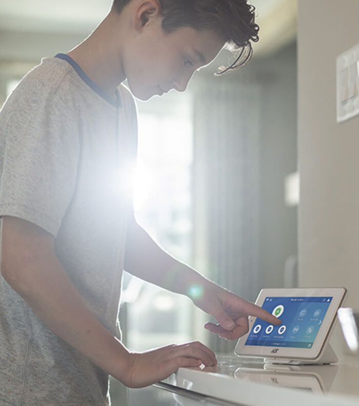 A young man is using a tablet computer in a kitchen.