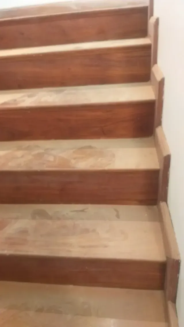 Escalera de madera con peldaños de color claro y molduras blancas a lo largo de la pared lateral.