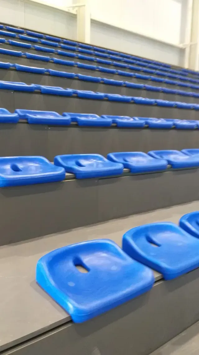 Asientos azules en gradas vacías dentro de un estadio deportivo.