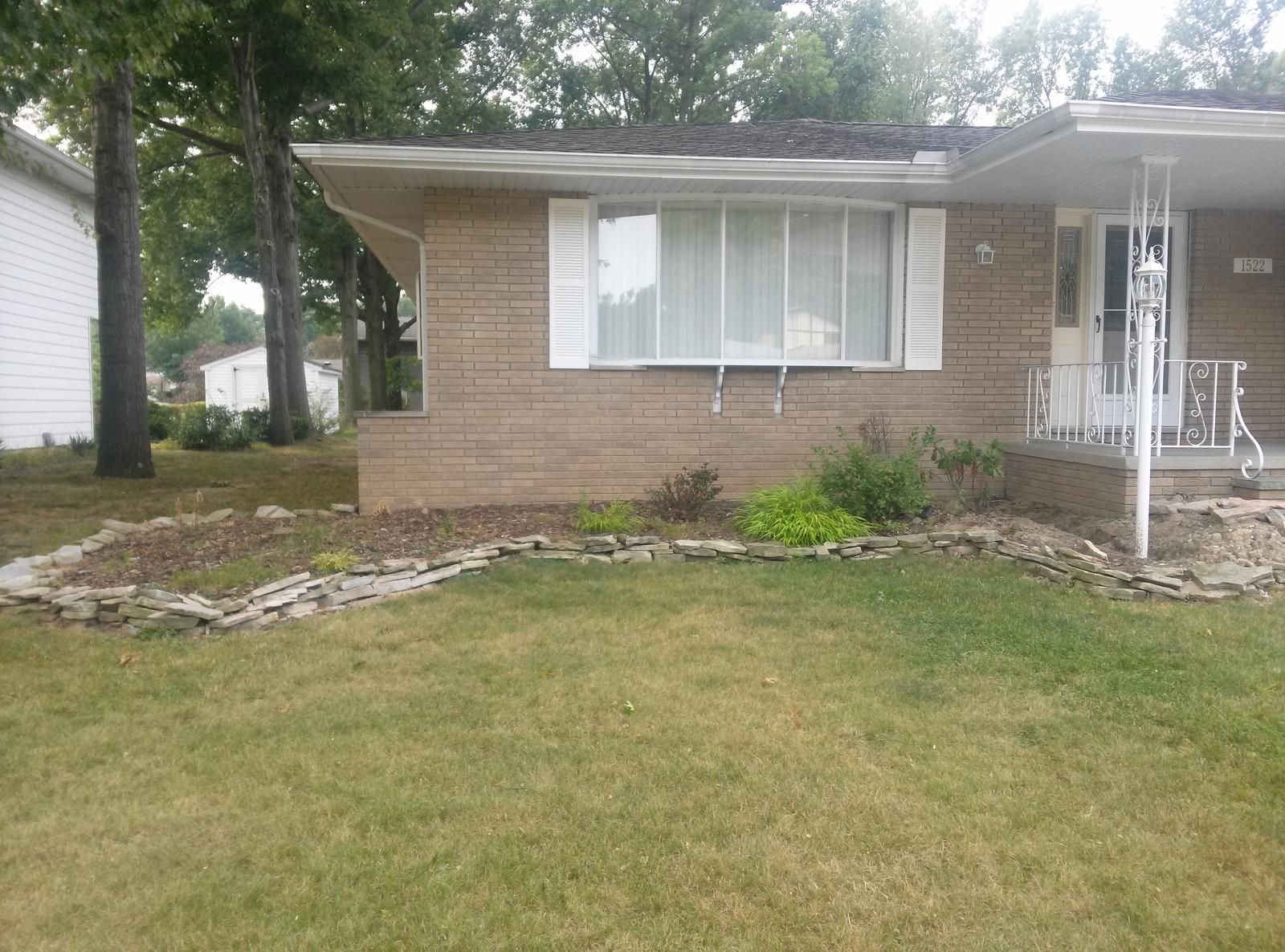 A one-story brick house with a flower bed.