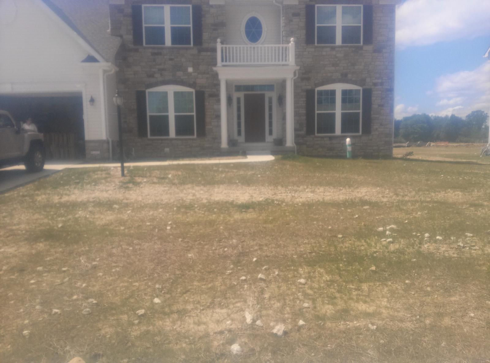 Two-story brick house with a brown lawn. Garage to the left. Sunny day.